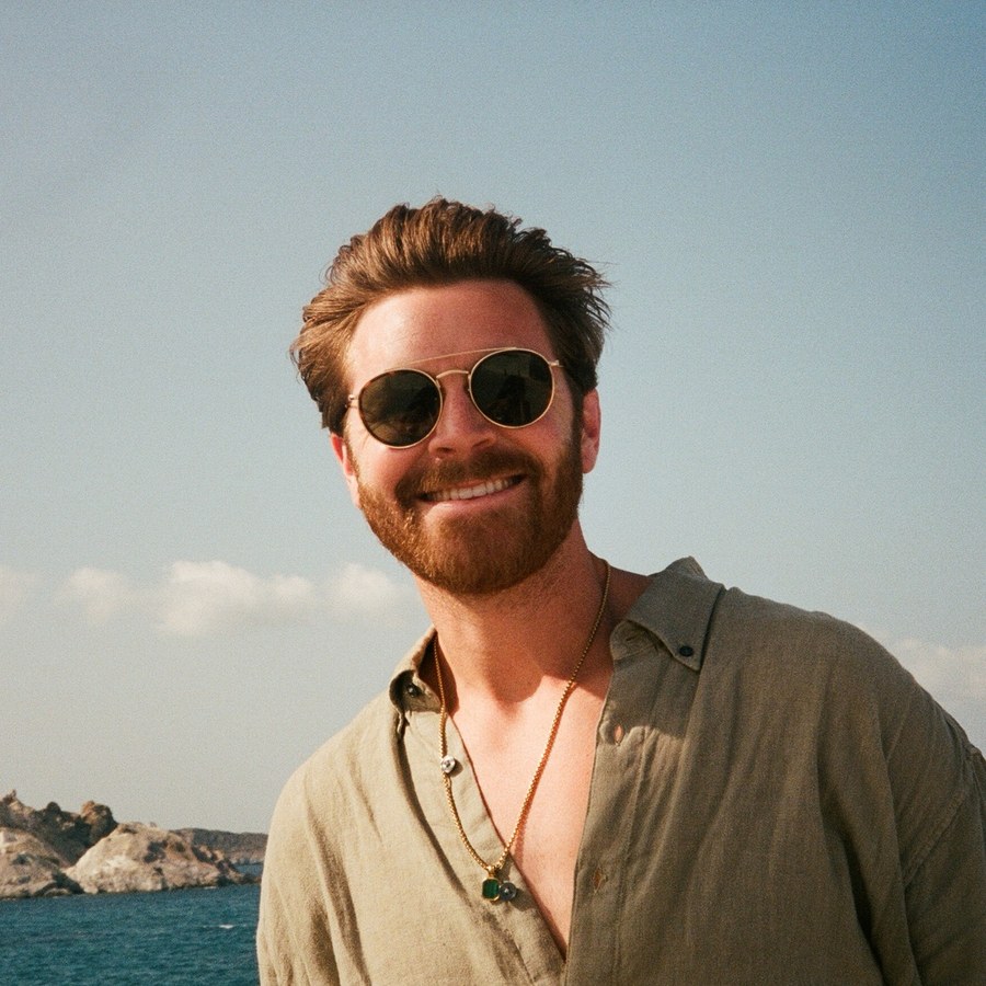 Jordan Tarver smiling in sunglasses by the sea