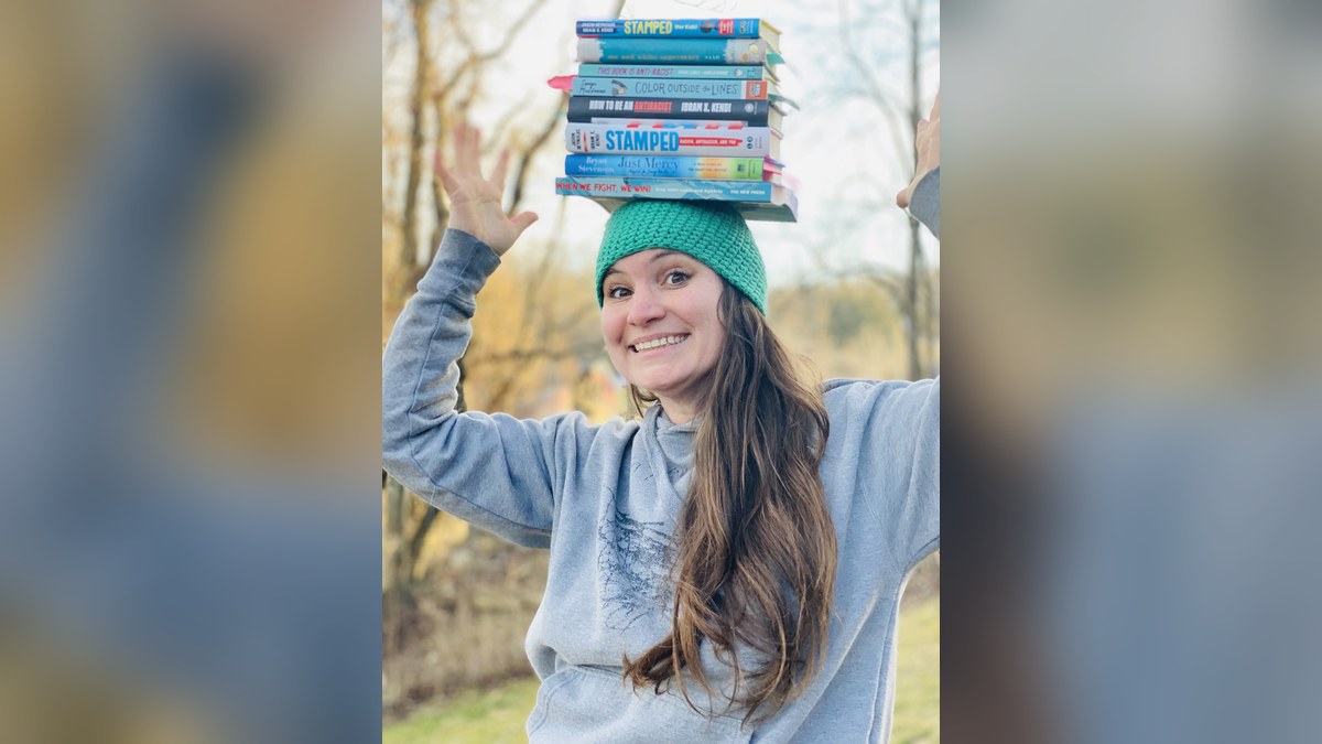 Lauren Burke, The Grant Gal, smiling with a stack of books balanced on her head